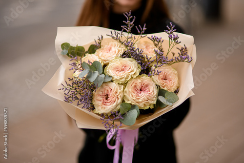 Wallpaper Mural Young woman dressed in black gently holding flower composition of roses, limonium and eucaliptus Torontodigital.ca