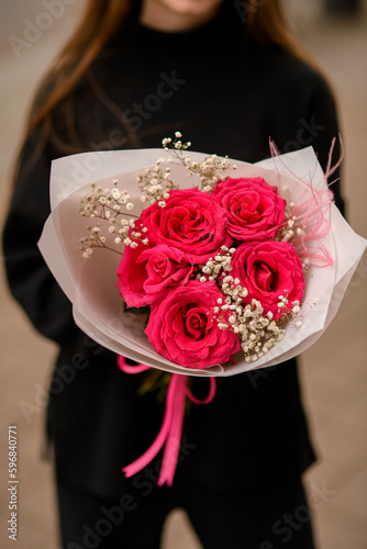 Photo of luxury composition of fresh red roses, white gypsofila and pink feathers photo