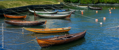 Photography A group of long, skinny, colorful boats tied up to shore and anchored to buoys in Stockholm Sweden
