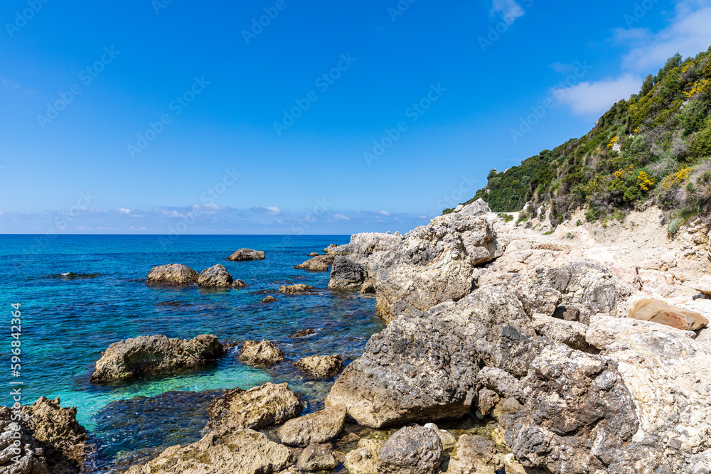 A beautiful landscape of the coast of the island of Corfu in the Ionian Sea of the Mediterranean in Greece. Pure blue clear water washes over the shores of the Greek island. A beautiful landscape of the coast of the island of Corfu in the Ionian Sea of the Mediterranean in Greece. Pure blue clear water washes over the shores of the Greek island.