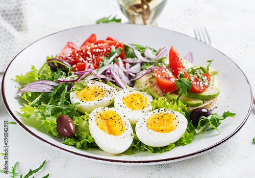 Fresh salad with tomato, olives, boiled eggs and and sandwich with ricotta cheese, avocado.
