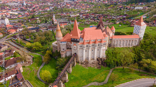 Aerial view of the Hunyad castle in Hunedoara, Romania in spring season, on a rainy day. Photography was shot from a drone with camera tilted downwards for a top view of the castle and surroundings.