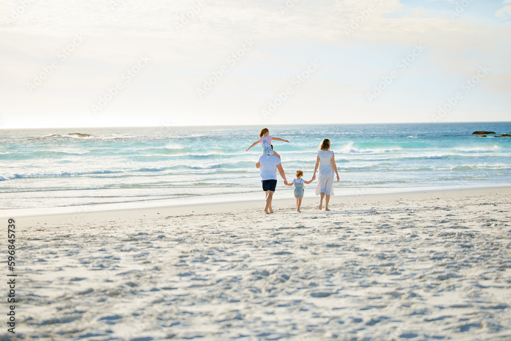 Happy family walking the beach. Rear view of young parents with children having fun on vacation. Little boy and girl enjoying summer with mother and father