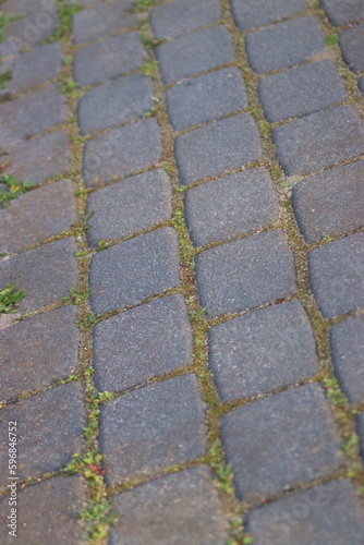 Dirty cobblestones, overgrown with weeds