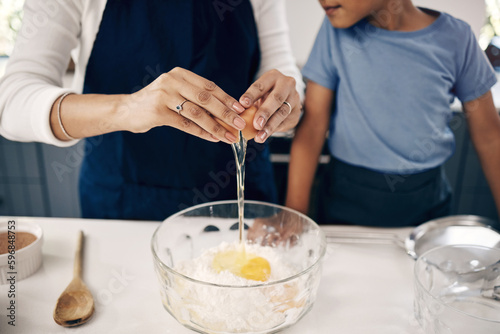 Canvas Print Closeup of female hands cracking a egg into a bowl while baking at home with her son