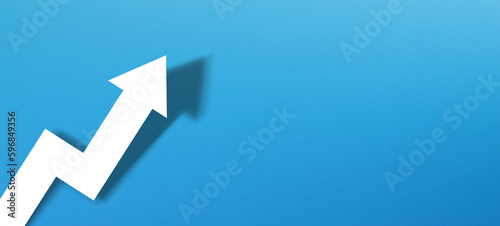 Business development and growth concept with white paper arrow on blue background photo