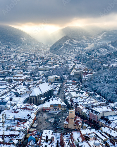 Aerial view of the main square in Brasov, in the winter with an epic sky in the background (sunrays through the clouds)