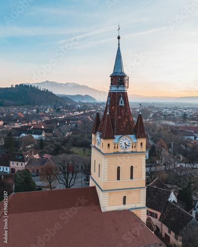 Aerial view of Cristian Lutheran Church in Transylvania at golden hour with the Bucegi mountains in the background 