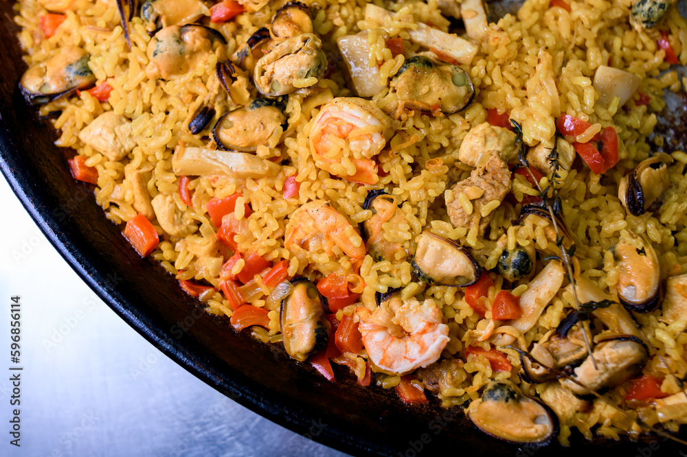 Spanish dish Paella in fry pan with rice, shrimp, mussels, vegetables and herbs