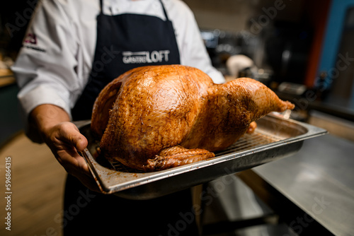 Fototapeta Naklejka Na Ścianę i Meble -  Waiter presents salver with whole roasted chicken with crispy crust