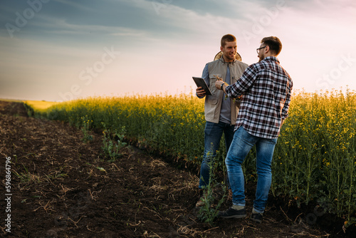 Two Caucasian man on a farmland doing some examination using digital tablet