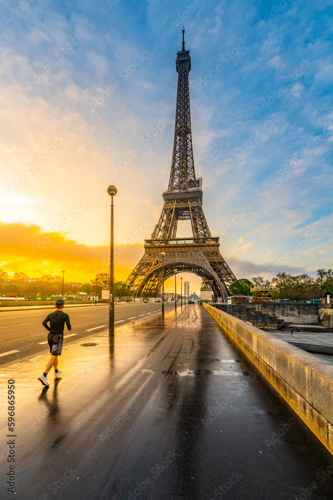 Young man run on the bridge at sunrise time after rain. Morning jogging under Eiffel Tower in Paris, France