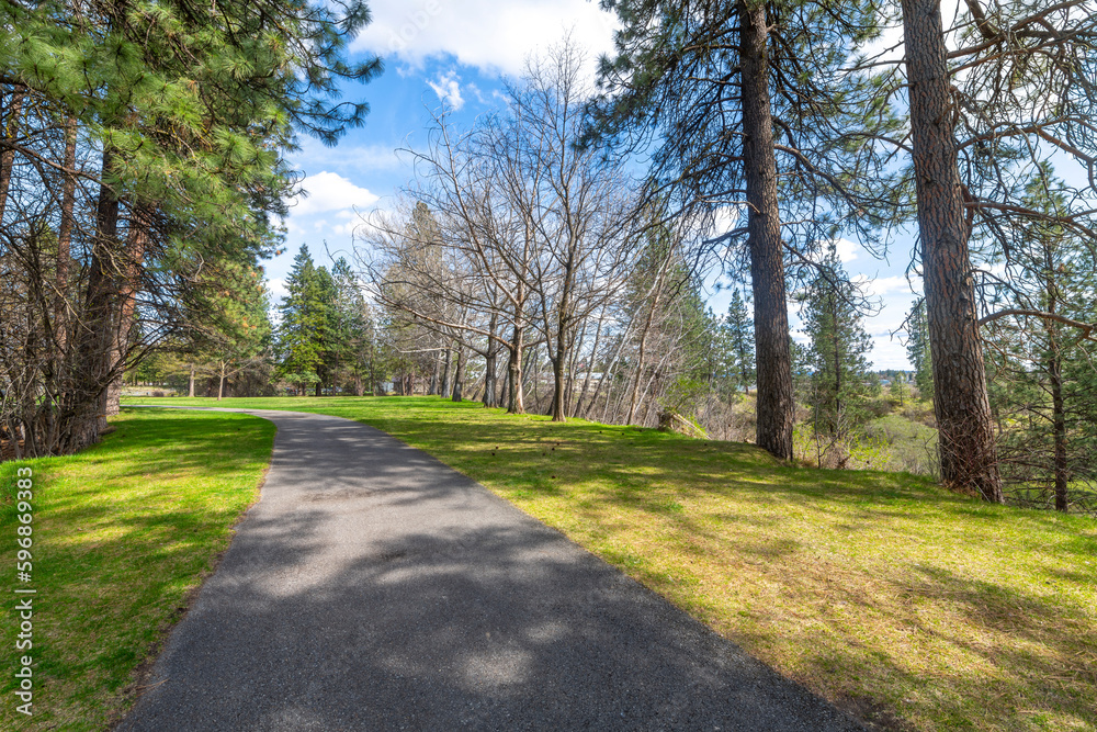 Paved walking trails through the grassy areas and woods at the riverfront Plante's Ferry Park along the banks of the Spokane River in Spokane Valley, Washington, USA. 