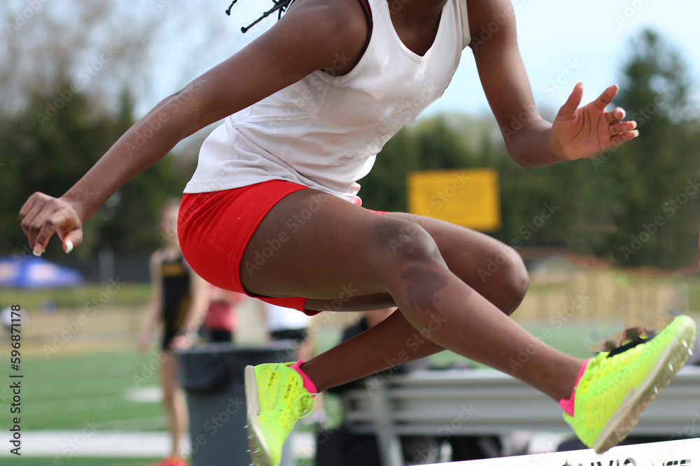 High school girl high above a hurdle during a track race
