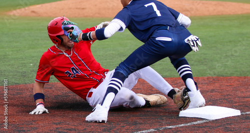 Baseball player sliding into thier base trying to avoid the tag photo