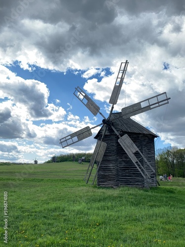 Ukrainian traditional wooden windmill on a green field with a blue sky