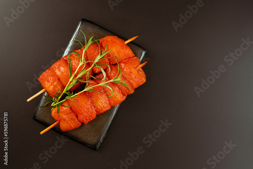 Fresh raw marinated chicken fillet skewers with fresh herbs on a black background..Food concept.Closeup of chicken meat.Procurement for designers.Chicken breast FilletsTop view.