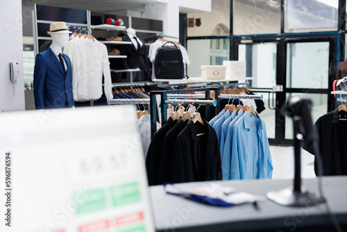 Modern boutique filled with formal wear, multiple racks with fashionable merchandise and trendy accessories. Interior of empty clothing store with stylish shirts on hangers, small business concept.
