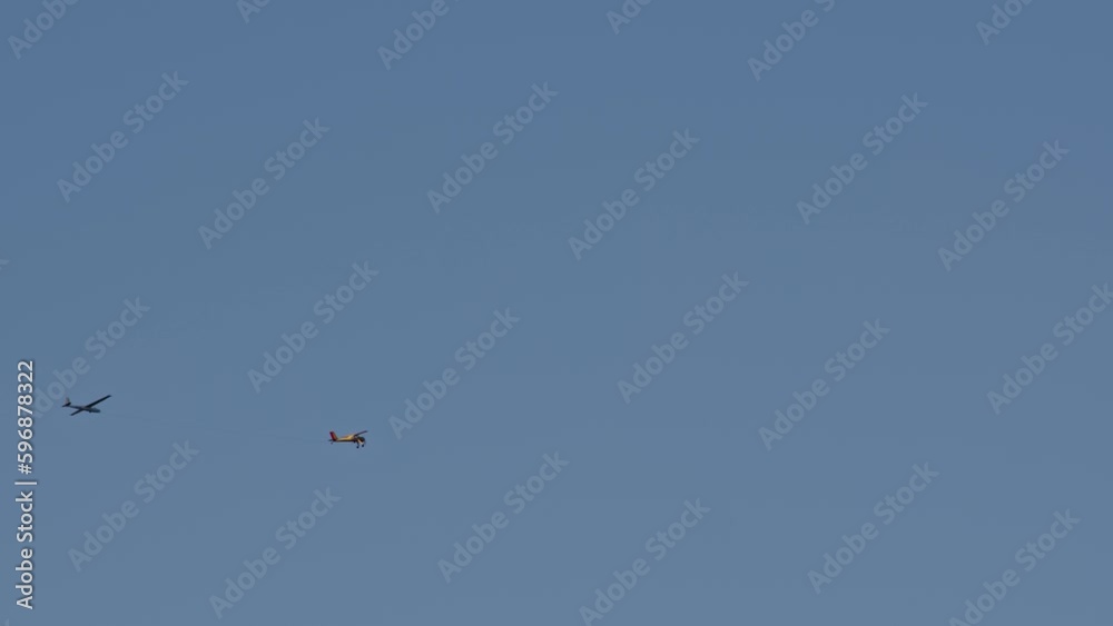 bright yellow plane pulls glider on cable, accelerating it to required speed so that glider can fly itself. Cloudy weather for flying for fun on airplane. bright yellow plane pulls glider on cable, accelerating it to required speed so that glider can fly itself. Cloudy weather for flying for fun on airplane.