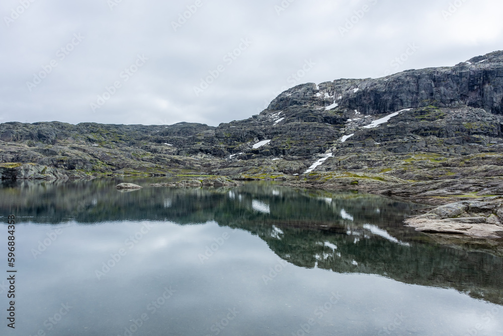 Reflection over a lake in moody vibe in the hike for Trolltunga,  Norway