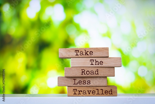 Wooden blocks with words 'Take The Road Less Travelled'. Inspirational motivational quote.
