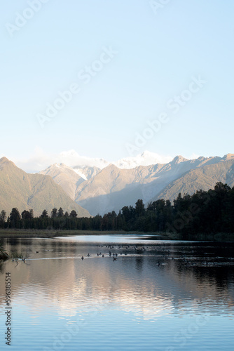 Landscape of a mountain lake with mountains and a glacier in New Zealand. The mountains are reflected in the lake.