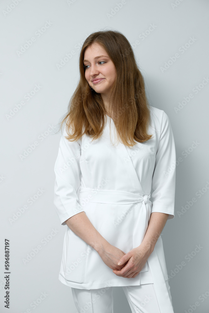 Vertical portrait of healthcare woman doctor, happy medical professional at hospital nurse workplace. Female doctor in white lab coat smiling and looking away against white wall. Vertical portrait of healthcare woman doctor, happy medical professional at hospital nurse workplace. Female doctor in white lab coat smiling and looking away against white wall.