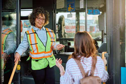 Foto Happy female bus driver talks to passenger at station.