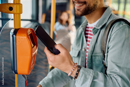 Close up of commuter validating card with smart phone while onboarding in bus photo