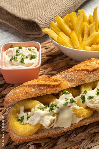 Typical Spanish calamari sandwich with mayonnaise and minced garlic and parsley. A little faded fries and glass of cold beer. Concept of tapas, fun and gastronomy.