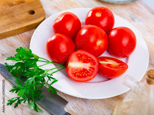 Ripe tomatoes on a plate during cooking, decorated with fresh parsley. Close-up image