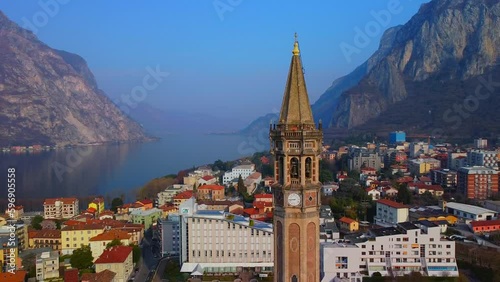 Aerial view of a beautiful european city near the shore of freshwater lake como in lombardy. Gothic church bell tower. Roofs of buildings. Mountains and rocks. Road by the water. Lecco Italy photo