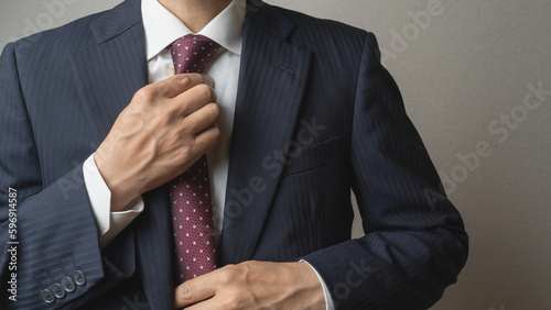 Fotografiet ネクタイを締めて身だしなみを整えるビジネスマン