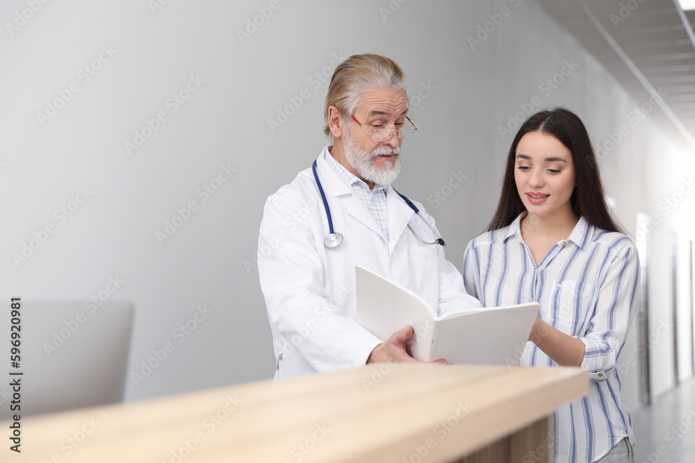 Senior doctor with notebook consulting patient in clinic Senior doctor with notebook consulting patient in clinic