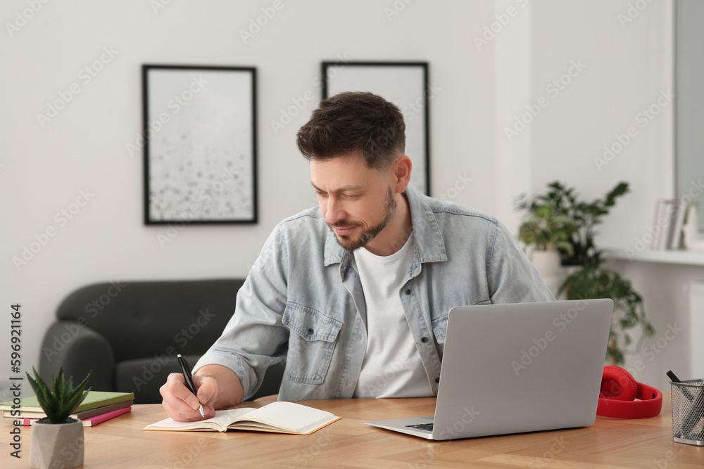 Online translation course. Man writing near laptop at home Online translation course. Man writing near laptop at home