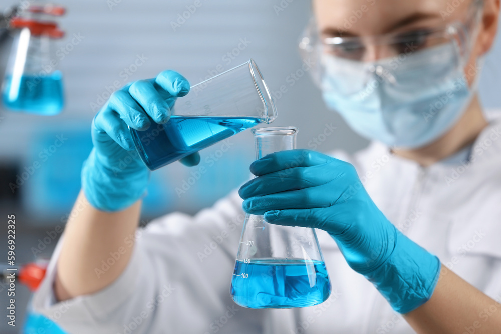 Scientist pouring sample into flask in laboratory, selective focus Scientist pouring sample into flask in laboratory, selective focus