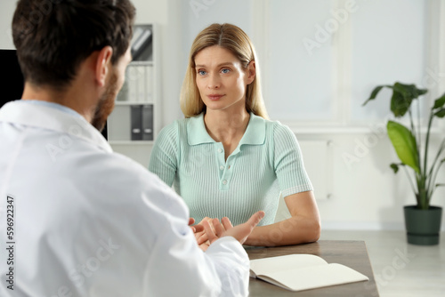 Doctor consulting patient at wooden table in clinic
