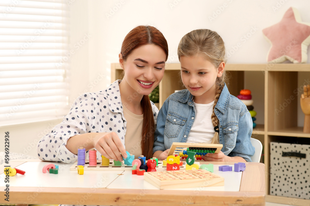 Fototapeta premium Happy mother and daughter playing with different math game kits at desk in room. Study mathematics with pleasure