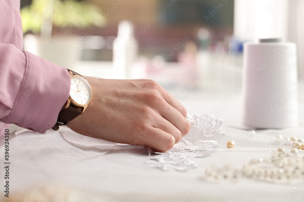 Obraz premium Dressmaker working with beautiful white lace at table in atelier, closeup