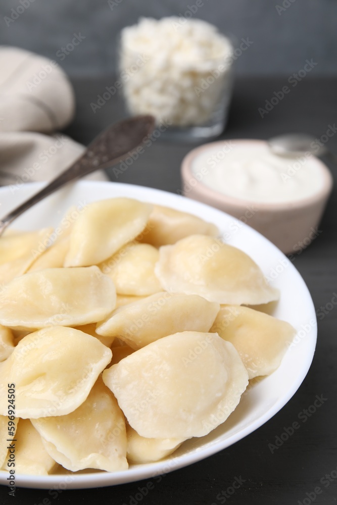 Plate of delicious dumplings (varenyky) with cottage cheese on wooden table, closeup