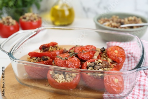 Delicious stuffed tomatoes with minced beef, bulgur and mushrooms in glass baking dish, closeup