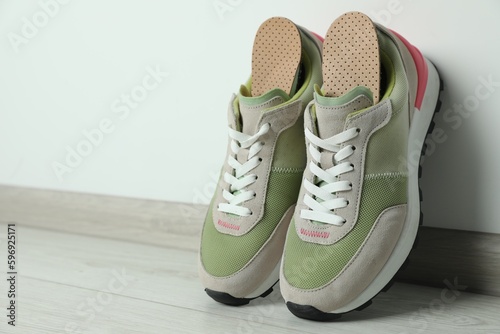 Orthopedic insoles in shoes on floor, closeup. Space for text