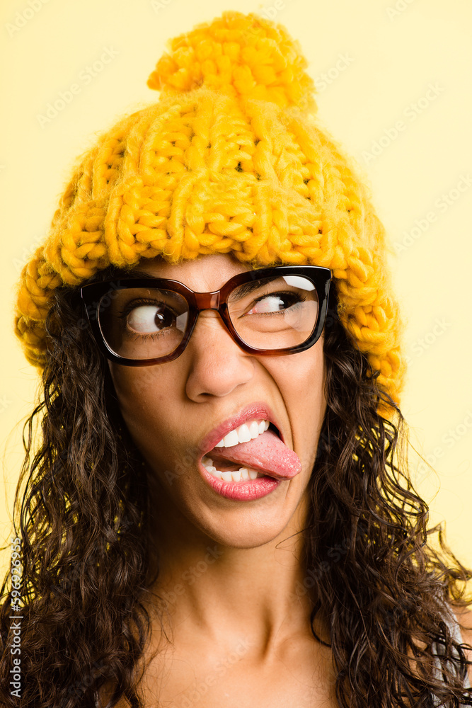 Yellow is such a playful colour. Shot of an attractive young woman standing alone in the studio and pulling funny faces while wearing a beanie.