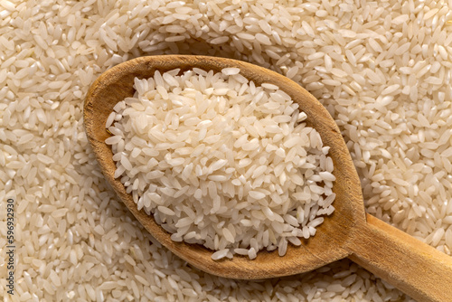 Carolina plantation rice texture background and wooden spoon, closeup. South Carolina golden rice.