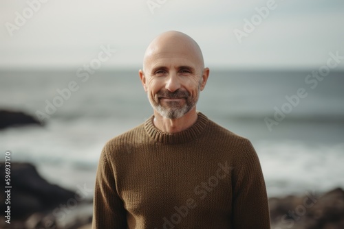 Portrait of a bald man with a beard in a sweater on the beach