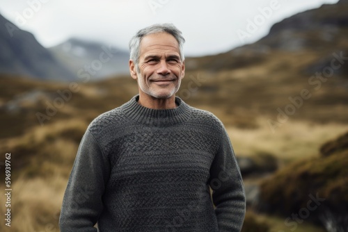 Portrait of a smiling senior man standing in the countryside on a cloudy day