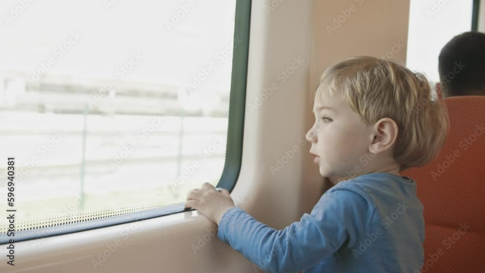 Curious little boy sitting on a train and looking out the window Curious little boy sitting on a train and looking out the window