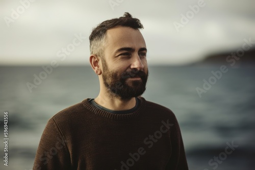 Portrait of a handsome bearded man in a sweater on the seashore