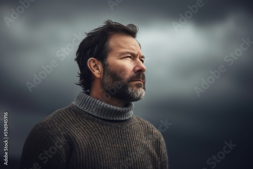 Portrait of a bearded man in a gray sweater on a dark background