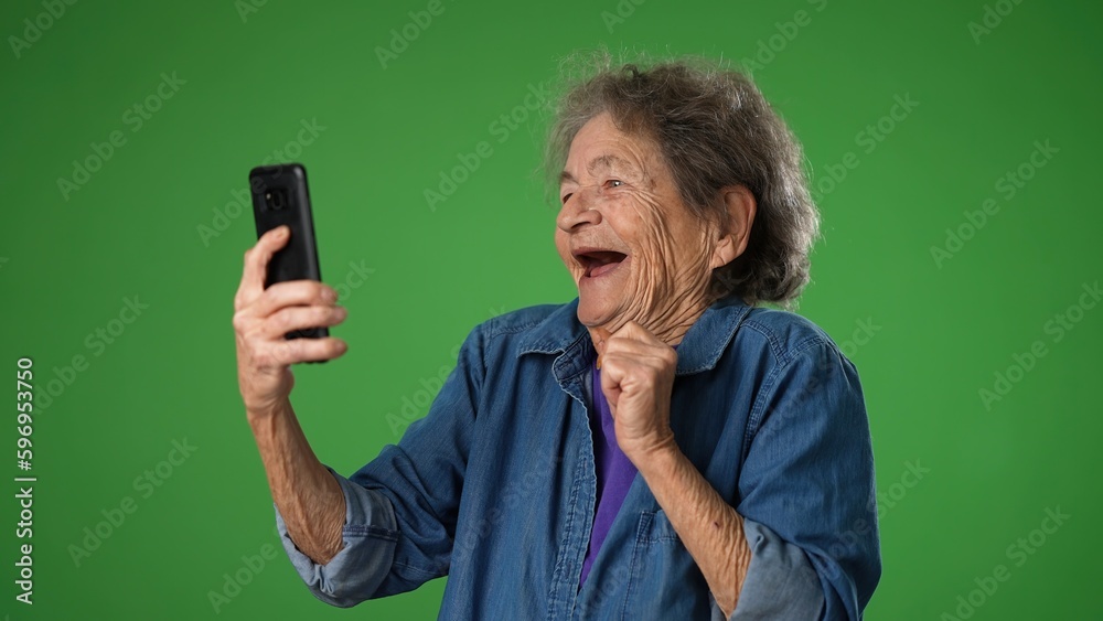 Funny crazy happy elderly old toothless woman taking selfie using mobile cell phone isolated on solid green screen background studio portrait. Funny crazy happy elderly old toothless woman taking selfie using mobile cell phone isolated on solid green screen background studio portrait.